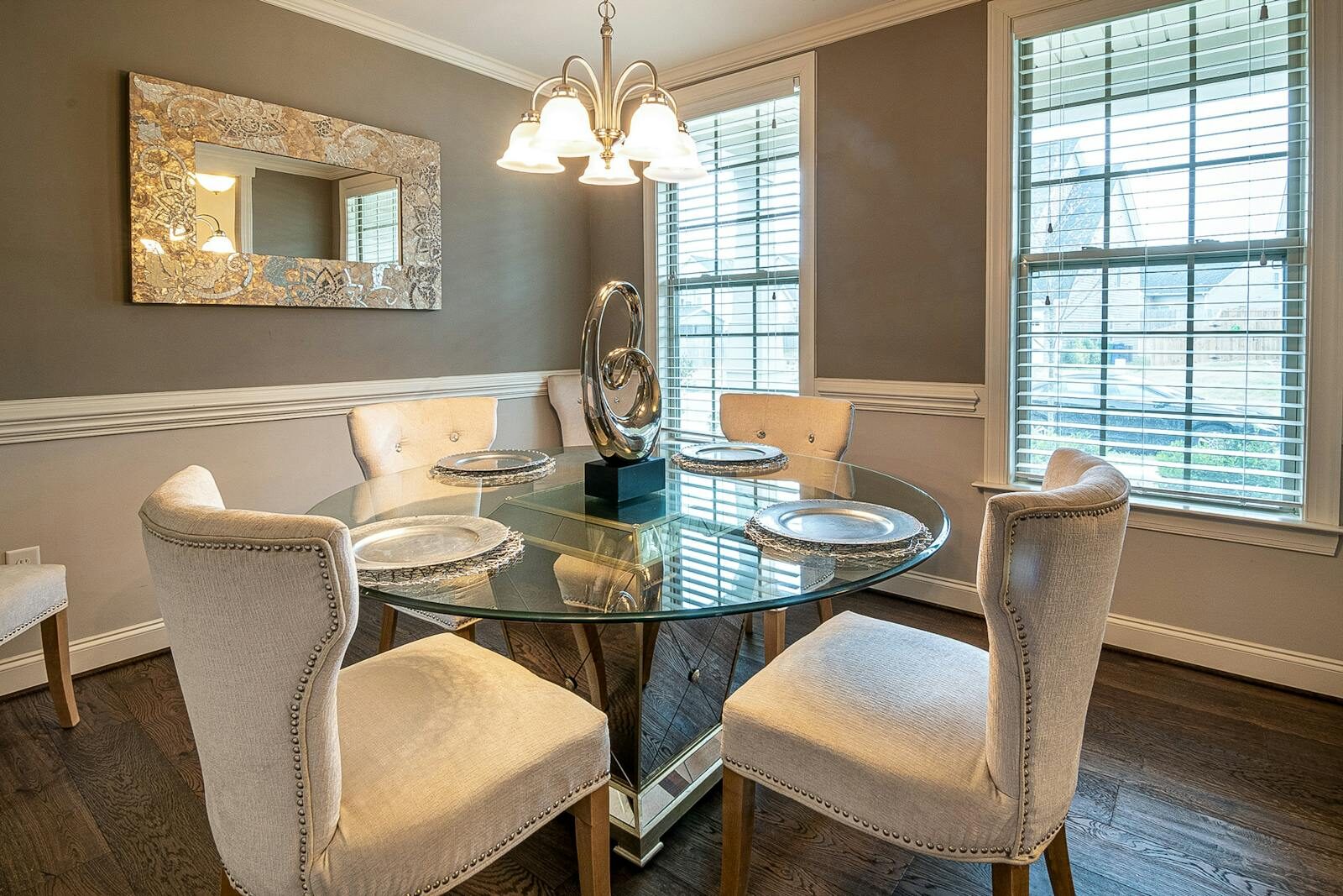 A stylish modern dining room featuring a round glass table and upholstered chairs with natural light.