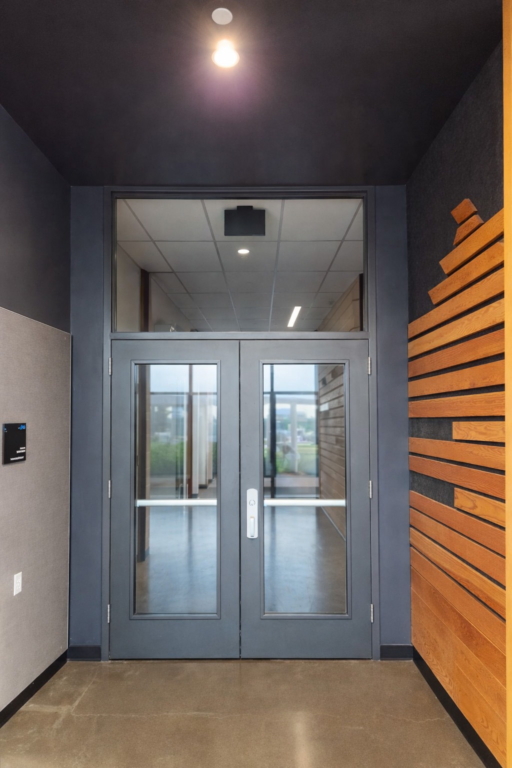 Modern entryway featuring sleek double doors and wood paneling. The design emphasizes light and openness, welcoming visitors to the space.